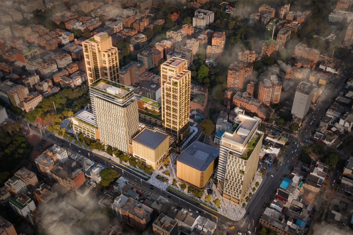 Vista aérea de ciudad con muchos edificios. En el centro hay un gran complejo moderno de torres altas y bloques bajos con terrazas verdes, rodeado de calles y árboles.