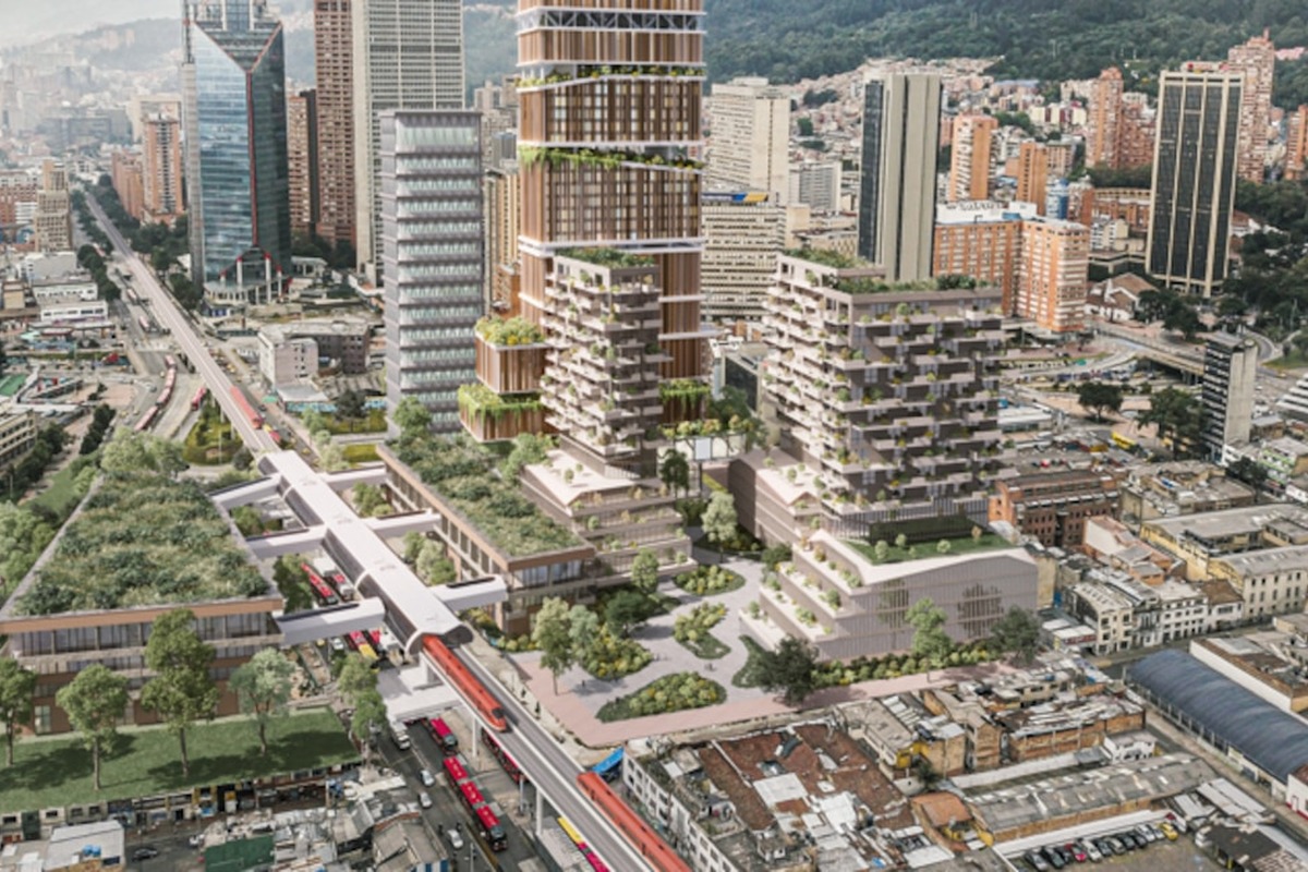 Vista aérea de ciudad densa con rascacielos modernos y edificios escalonados con terrazas verdes; al frente, estación elevada con buses rojos y puentes peatonales sobre avenidas y casas bajas.