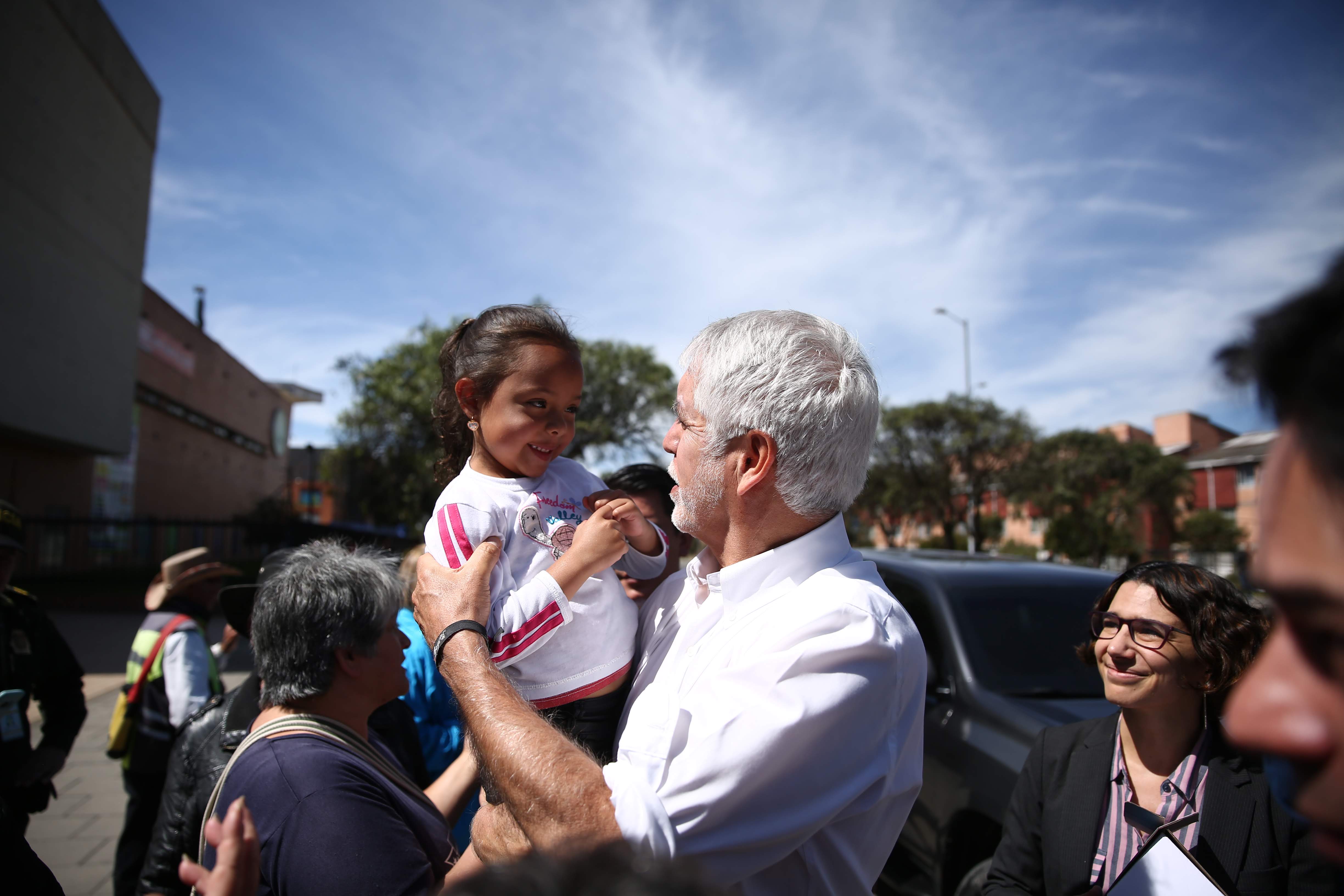Alcalde Enrique Peñalosa alzando una niña de una de las familias beneficiarias